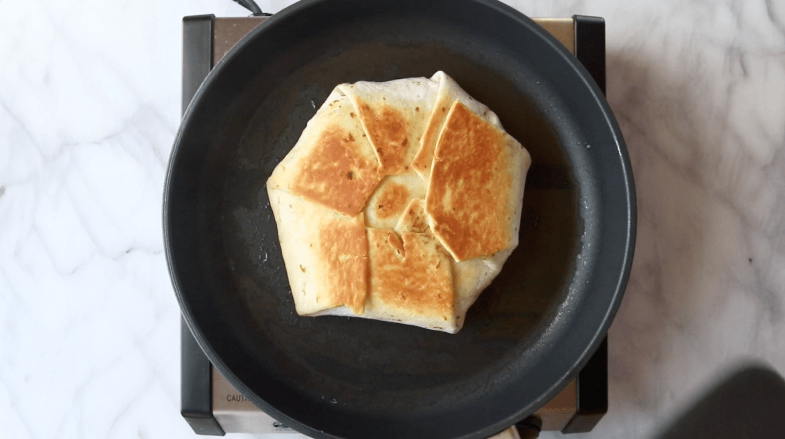 Fried crunchwrap in a skillet.