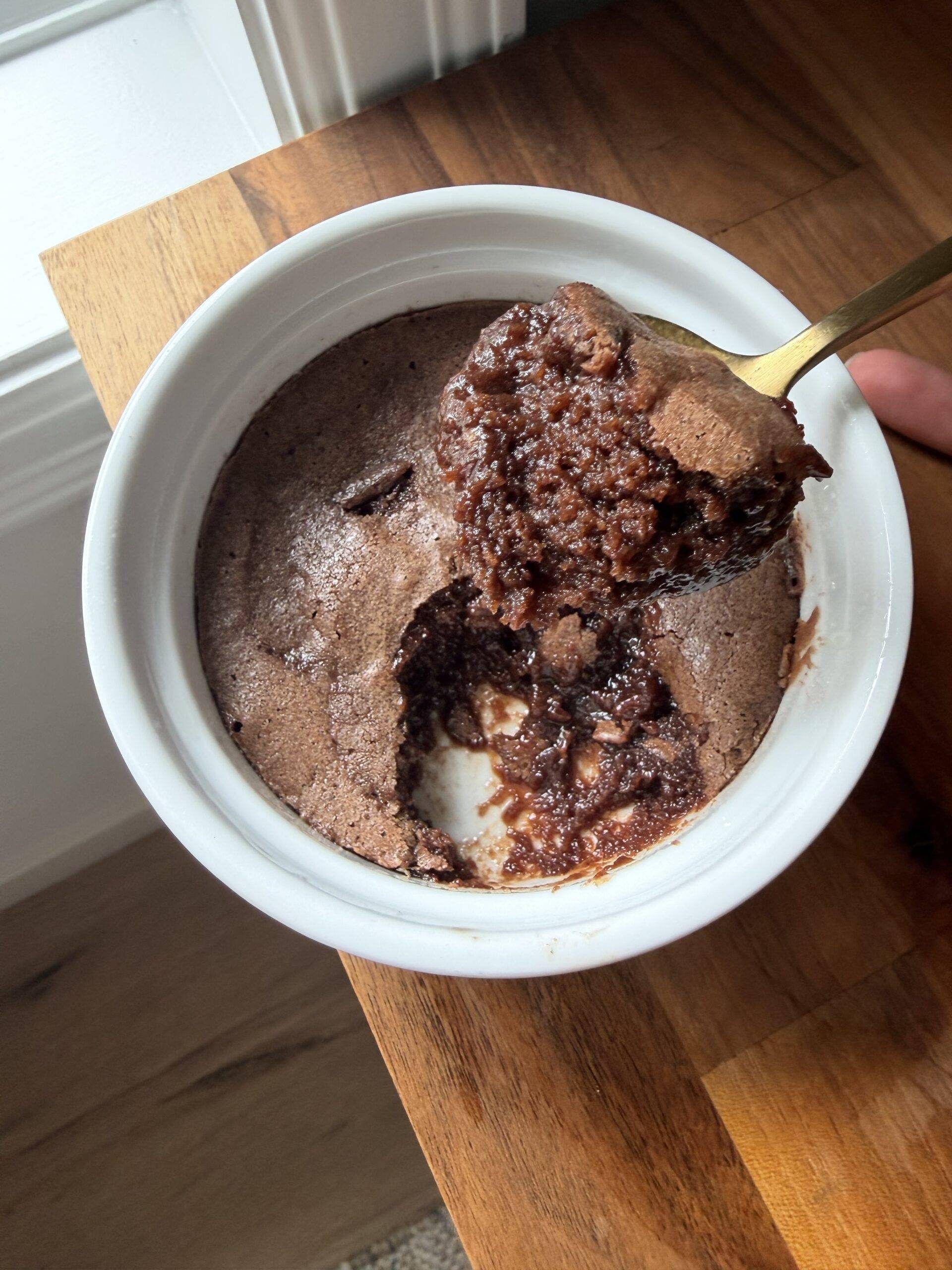 Scooping brownie pudding out of a ramekin.
