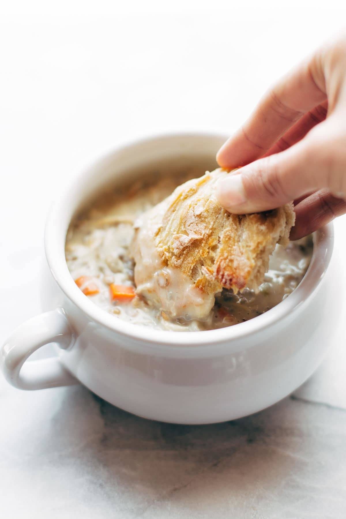 Bread being dunked in soup.
