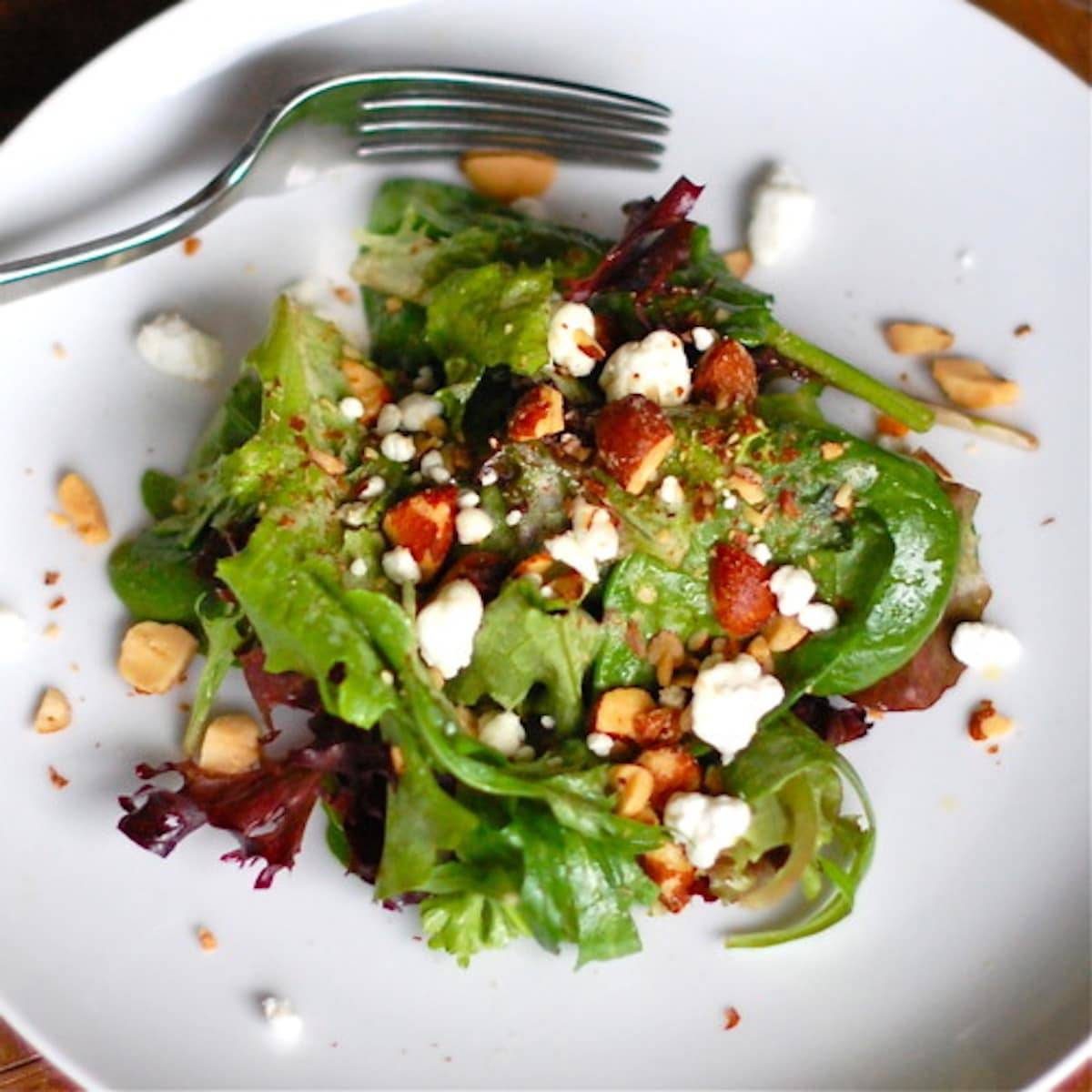 Smoked almond and goat cheese salad on a plate with a fork.
